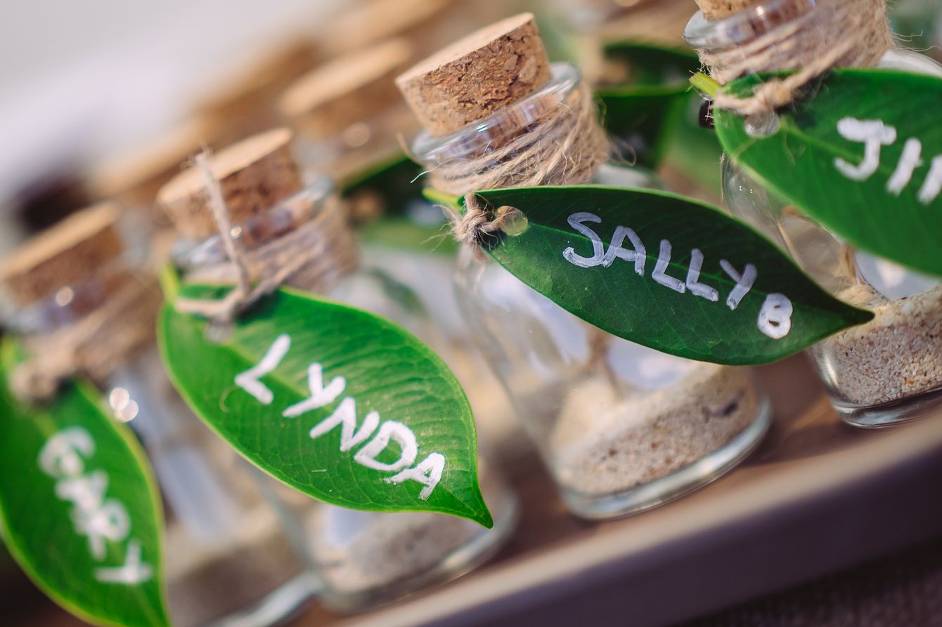 Heiraten in Thailand - Kleine Gastgeschneke in kleinen Gläschen mit Namensschildern aus Blättern.