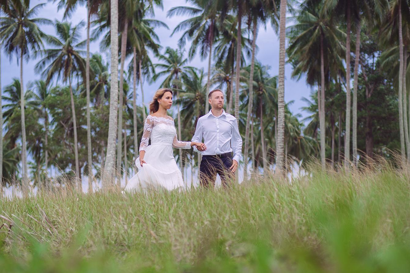 Brautpaar spaziert in Palmenhainen in Phuket