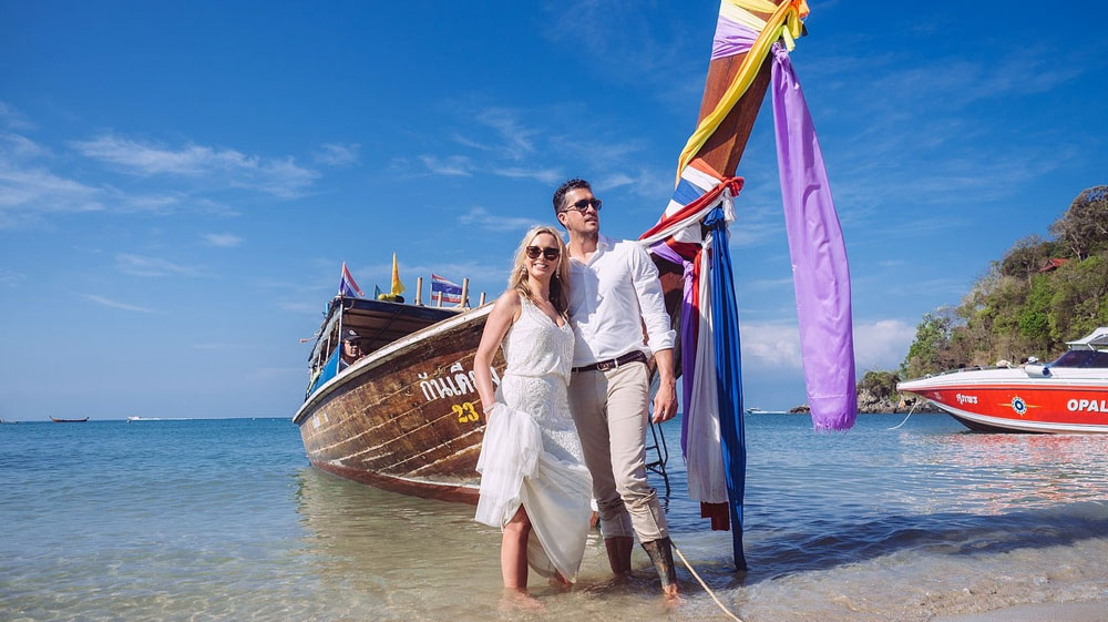 Hochzeit zu zweit. Brautpaar lehnt an einem Longtail Boot am Strand von Koh Lanta