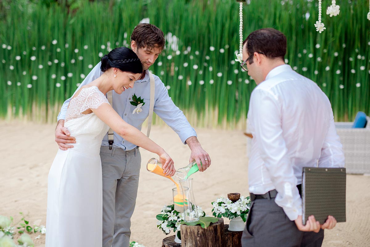 Sandzeremonie Hochzeit - Braut und Bräutigam gießen die Sande in das Gefäß ein