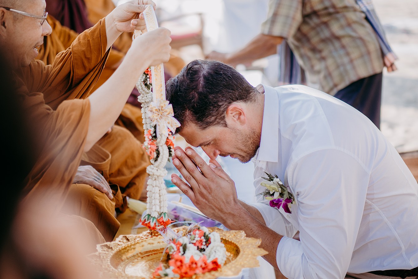 Buddha Wedding Thailand- Mönch hängt Bräutigam Blumengirlande um