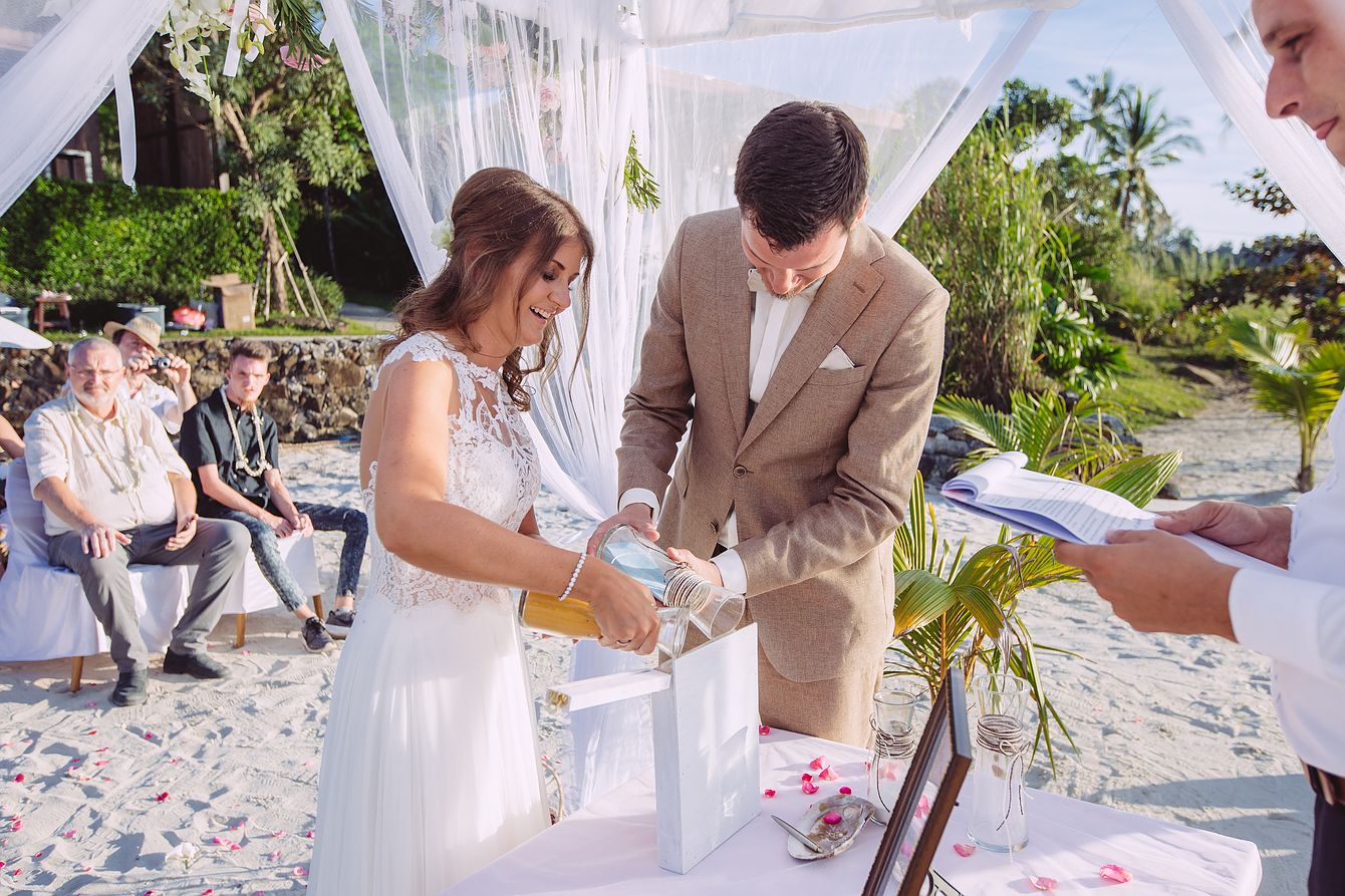 Hochzeit am Strand. Das Brautpaar schüttet Sande in ein Gefäß bei der Sandzeremonie